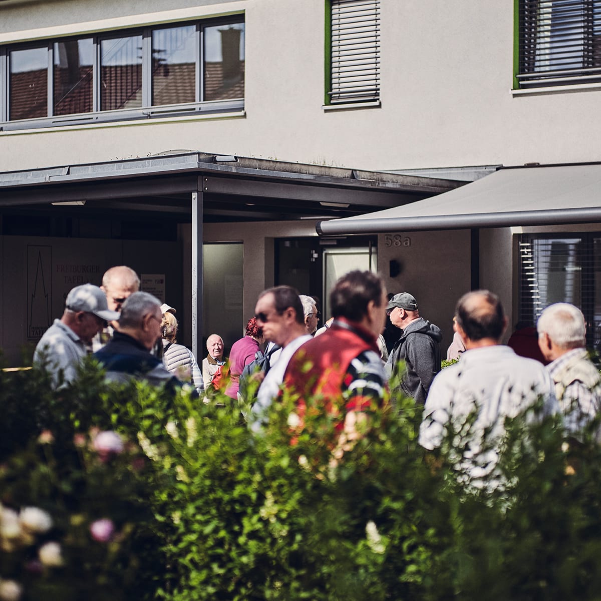 Menschen stehen vor dem Eingang und unterhalten sich.