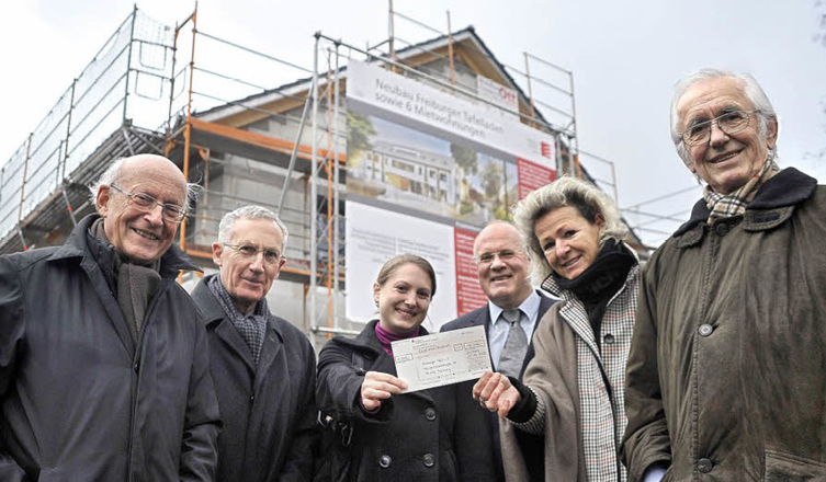 Eine Gruppe steht vor der Baustelle des neuen Freiburger Tafelladens.