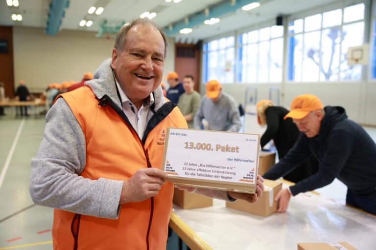 Ein glücklicher Ehrenamtlicher der Hilfemacher hält das 13.000 Paket der Hilfemacher in der Hand.